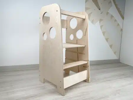 Tanulótorny natur fa színben. A tanulótorony egy üres szobában van a fal előtt. A tanulótorny nyírfa lemezből készült, ami átalakítható székké vagy asztallá